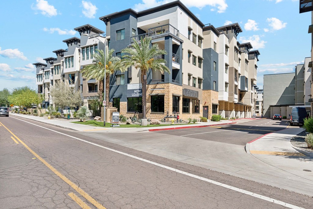 an empty street in front of an apartment building with palm trees