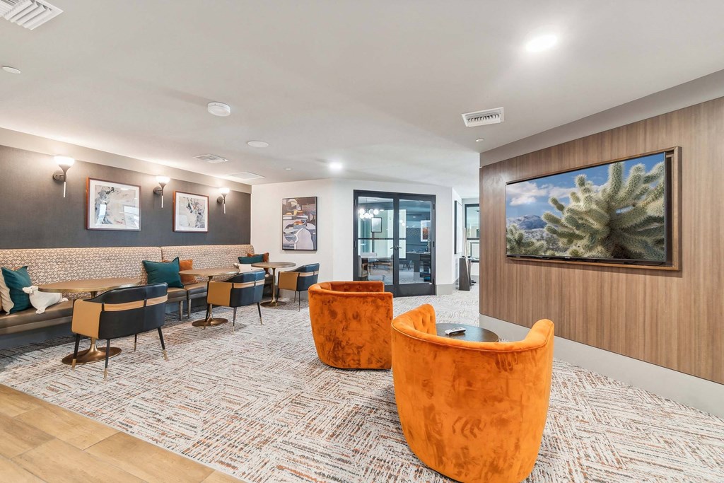 a lounge area with chairs and tables and a painting on the wall