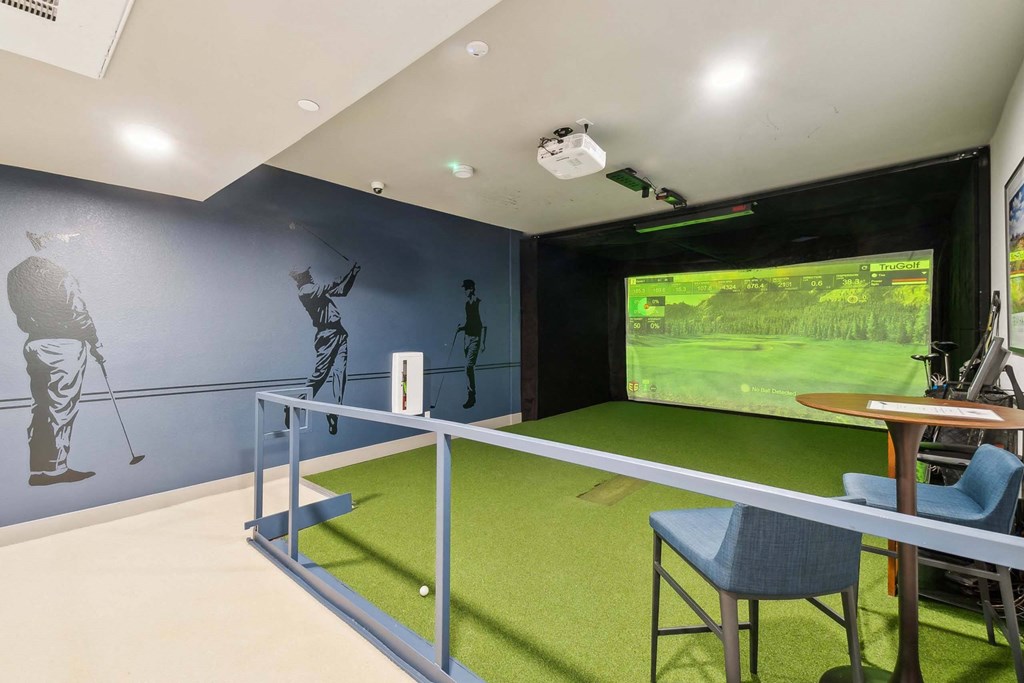 a game room with a golf simulator and a tv