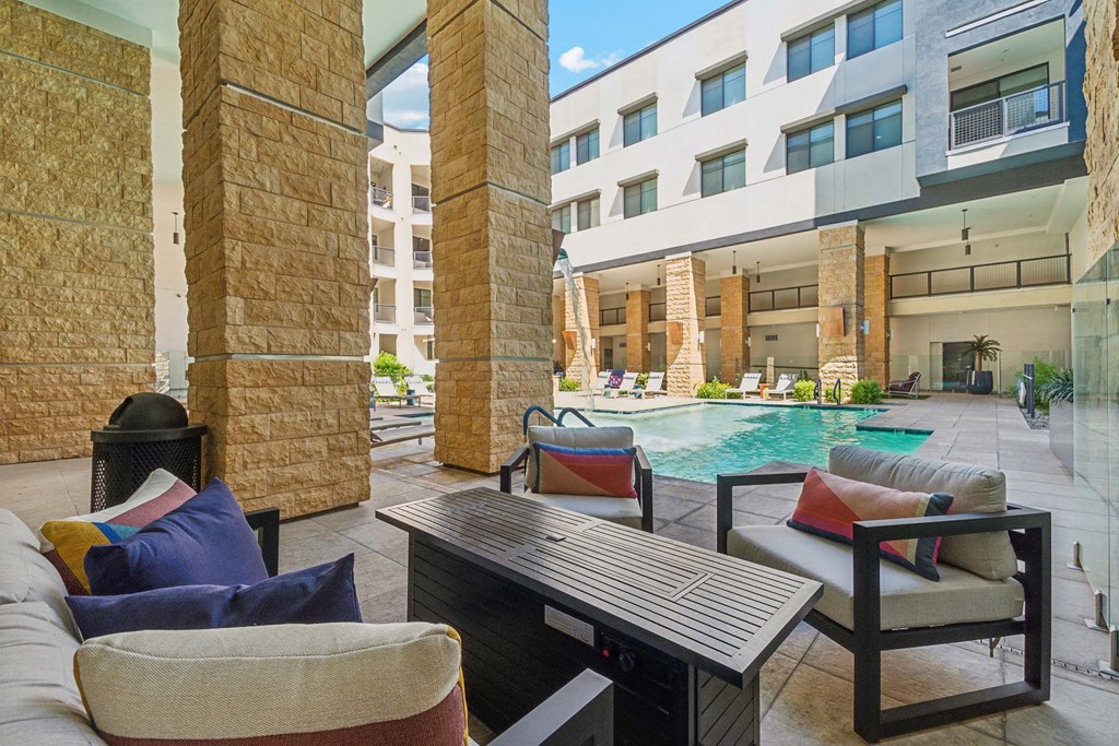 a patio with a pool and furniture in front of a building