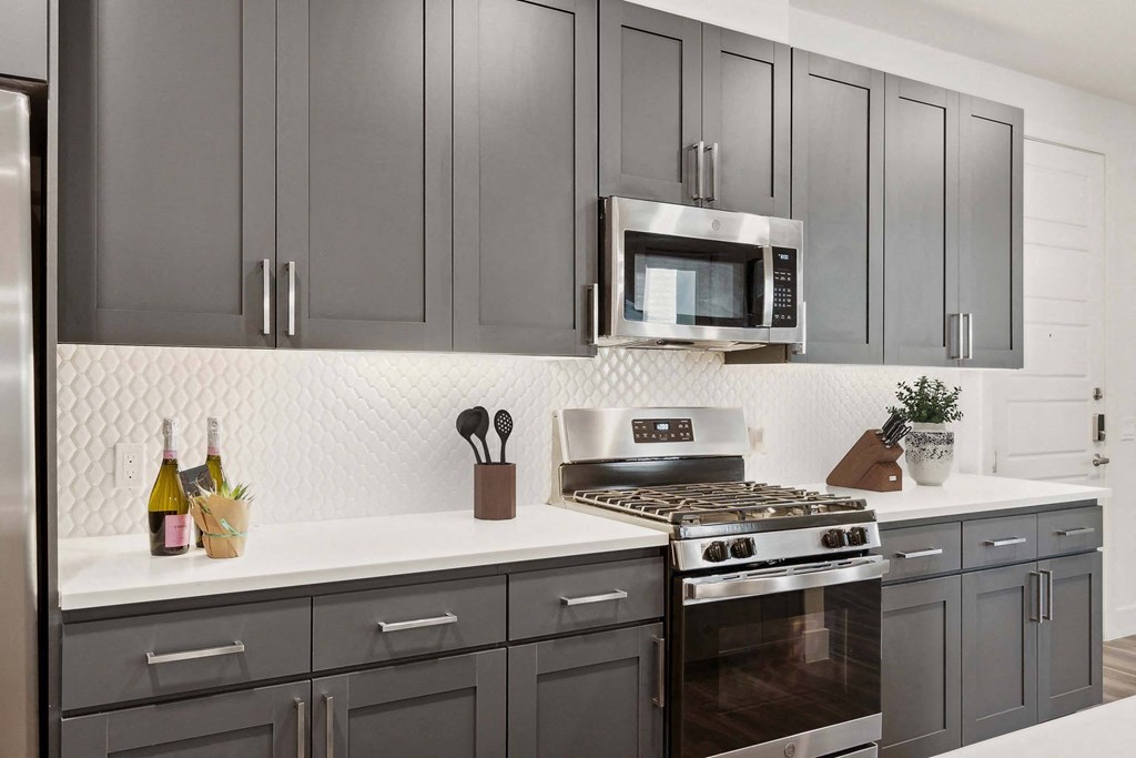 a kitchen with gray cabinets and a stove and a microwave
