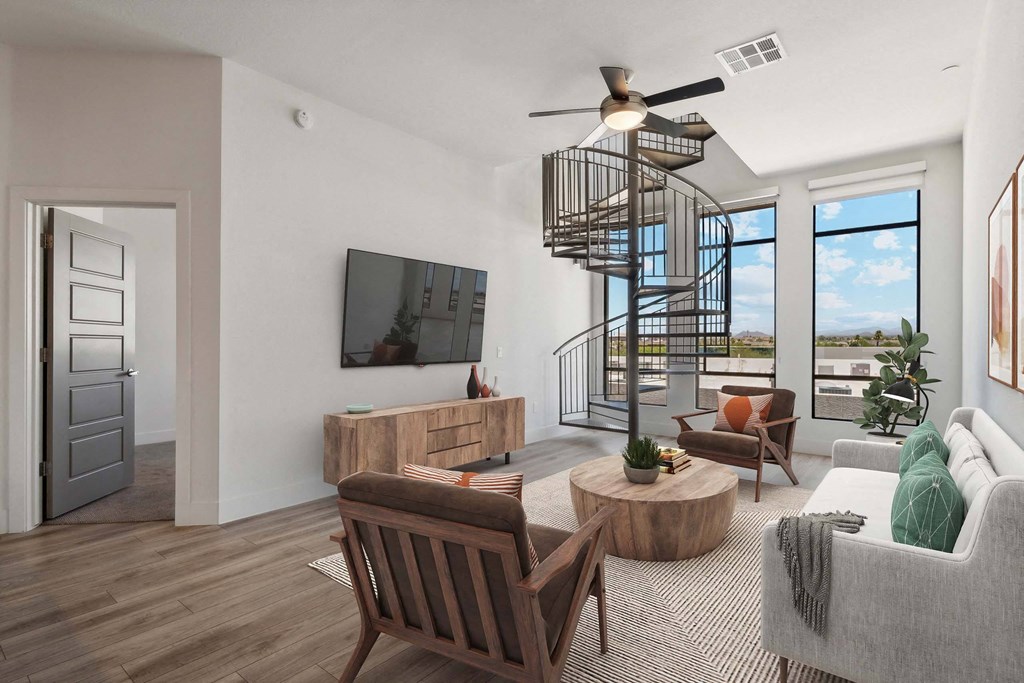 a living room with a spiral staircase in the background and a couch and chairs