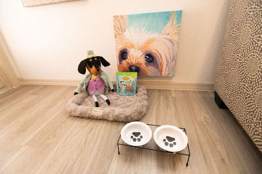 a dog sitting on a bed in front of a painting of a dog