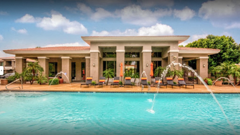 a swimming pool with water fountains in front of a hotel