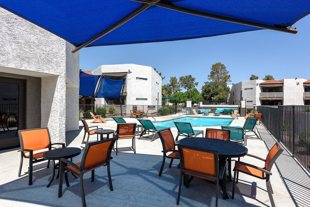 our apartments have a large pool and patio with tables and chairs