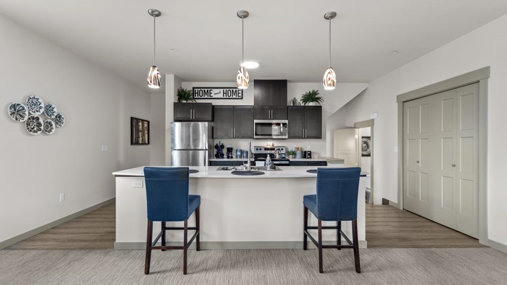 A kitchen with a white counter and blue chairs.