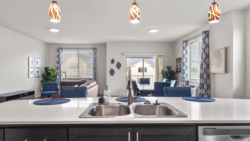 A modern kitchen with a large island and a view of the living room.