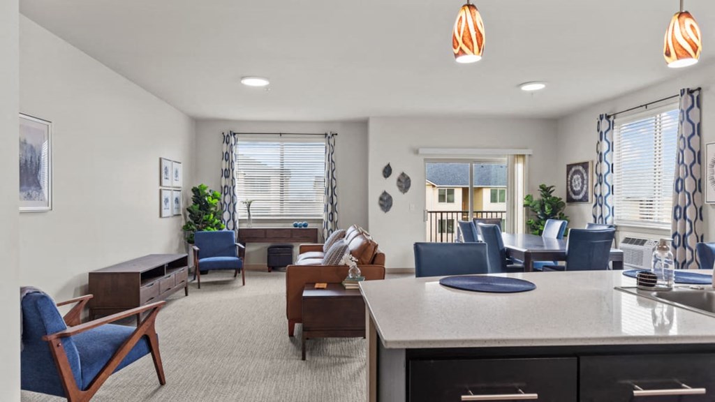 A well-lit room with a kitchen island and chairs.