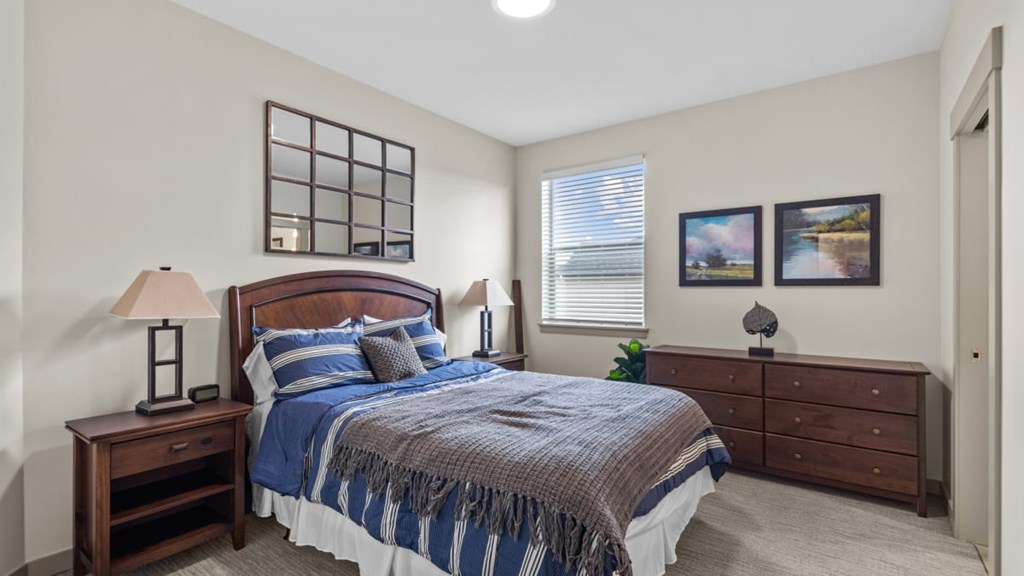 A bedroom with a bed, nightstand, and lamp.