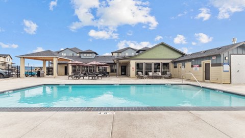 Lark View Village Apartments in Eugene, OR Large swimming pool in front of a building with a covered patio area.