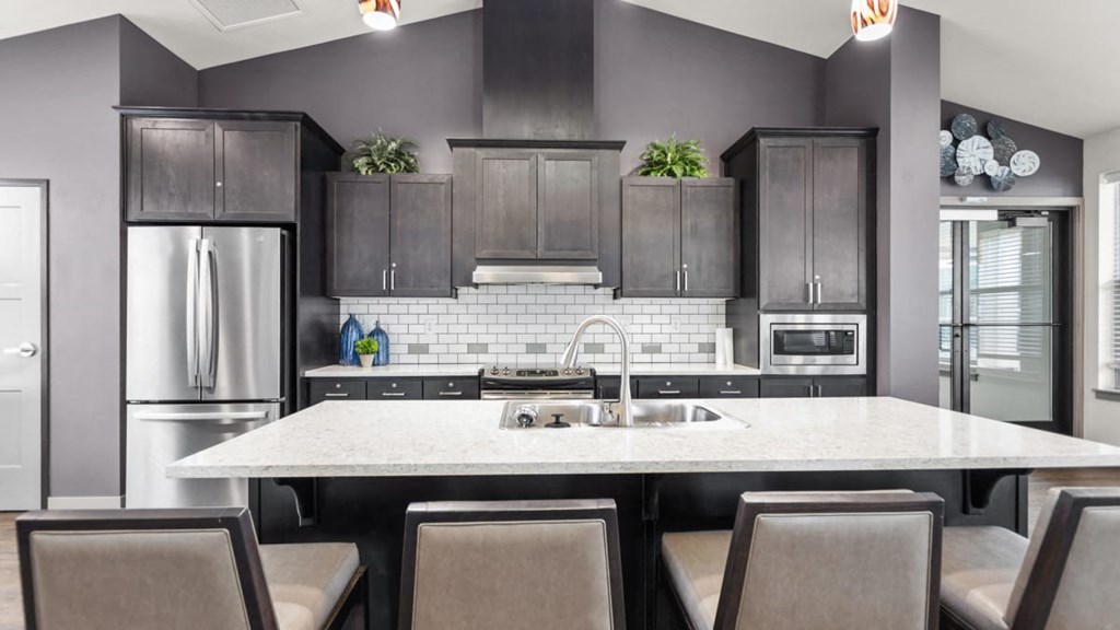 A modern kitchen with a large island and dark cabinets.