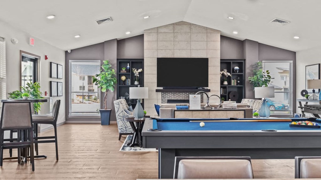 A well-lit room with a pool table and a television.
