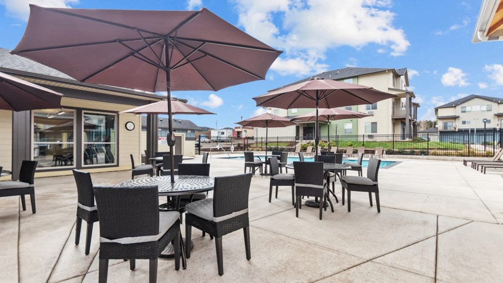 A patio with tables and chairs under umbrellas.