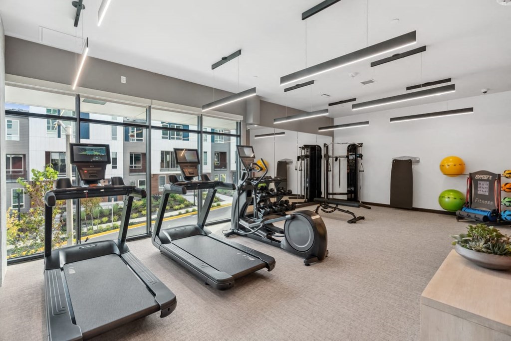 A gym with treadmills, exercise equipment, and a bowl of fruit. A gym with treadmills, exercise equipment, and a bowl of fruit at Cru at Willows Apartments, Redmond, Washington