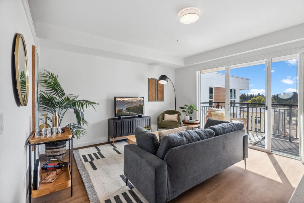 A living room with a grey couch and a flat screen TV at Cru at Willows Apartments, Redmond, Washington, 98052