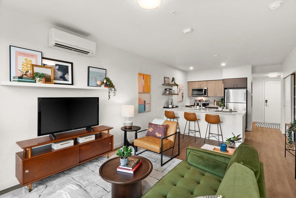A living room with a green couch and a wooden entertainment center at Cru at Willows Apartments, Redmond, WA