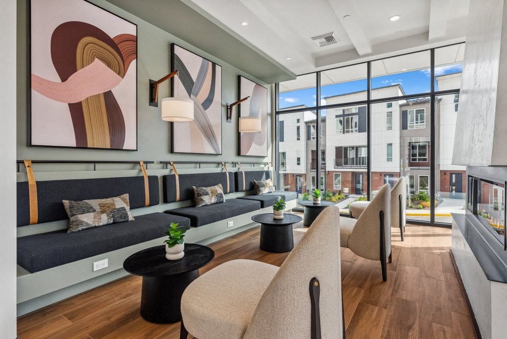 A modern living room with a large window and a view of a building outside at Cru at Willows Apartments, Redmond, 98052