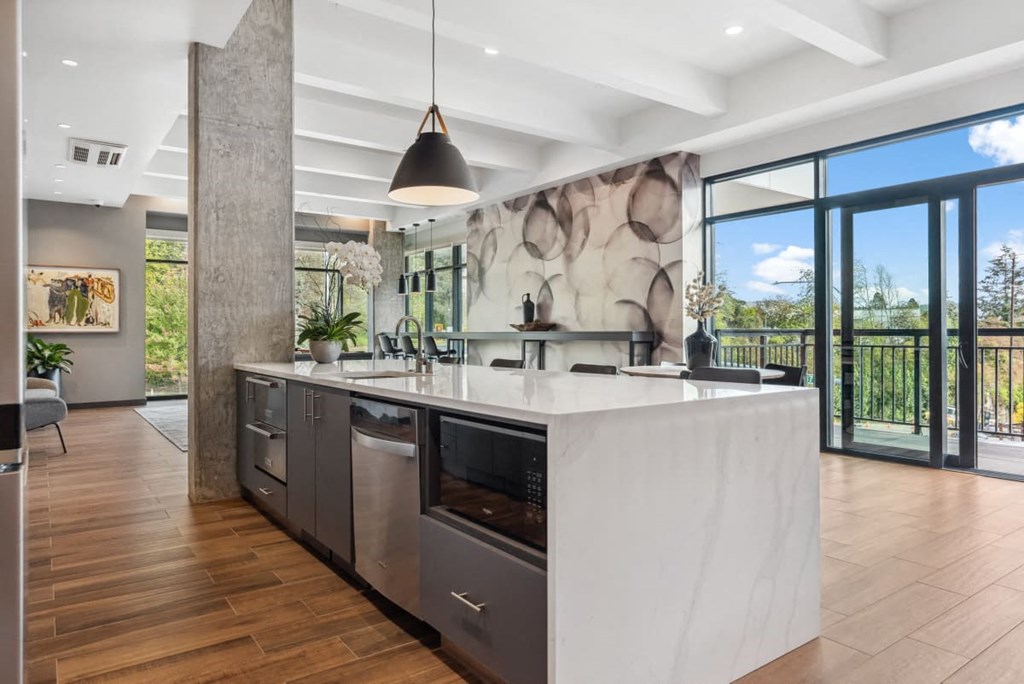 A modern kitchen with a large island and a view of the outdoors at Cru at Willows Apartments, Redmond, Washington