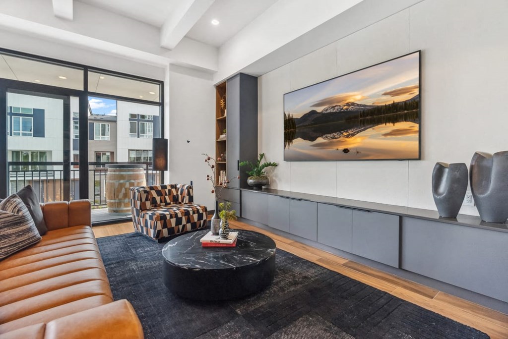 A modern living room with a large painting on the wall and a black coffee table in the center at Cru at Willows Apartments, Washington
