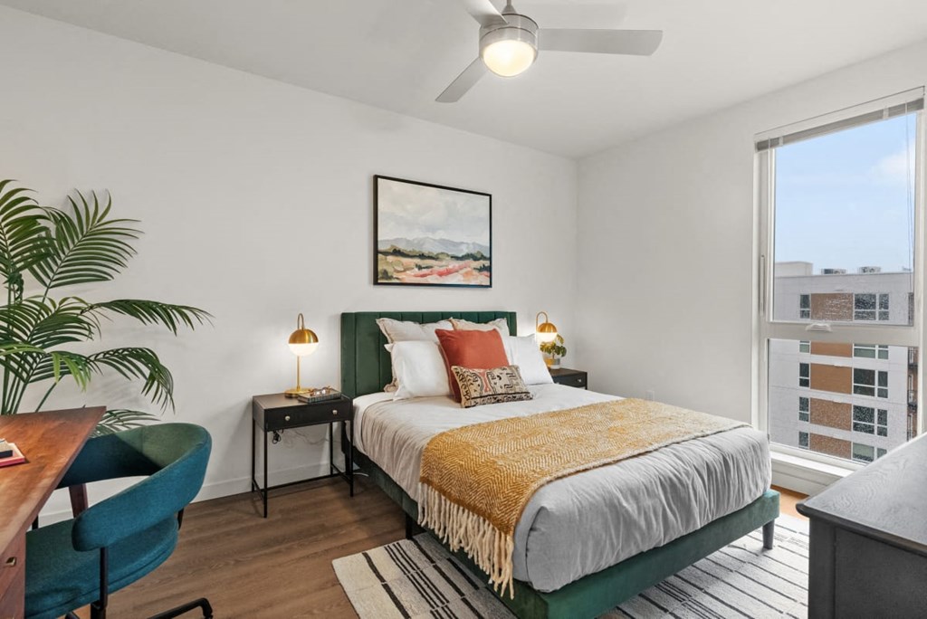 A bedroom with a bed, a chair, a desk, and a ceiling fan at Cru at Willows Apartments, Redmond