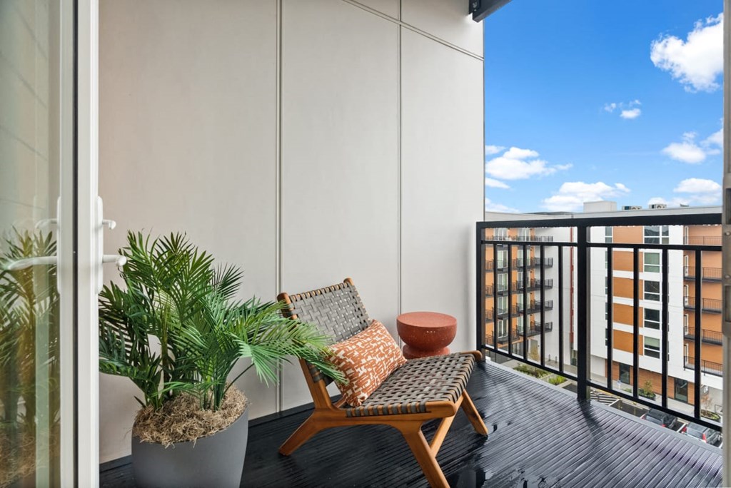 A balcony with a chair, potted plant, and a cushion at Cru at Willows Apartments, Redmond, Washington