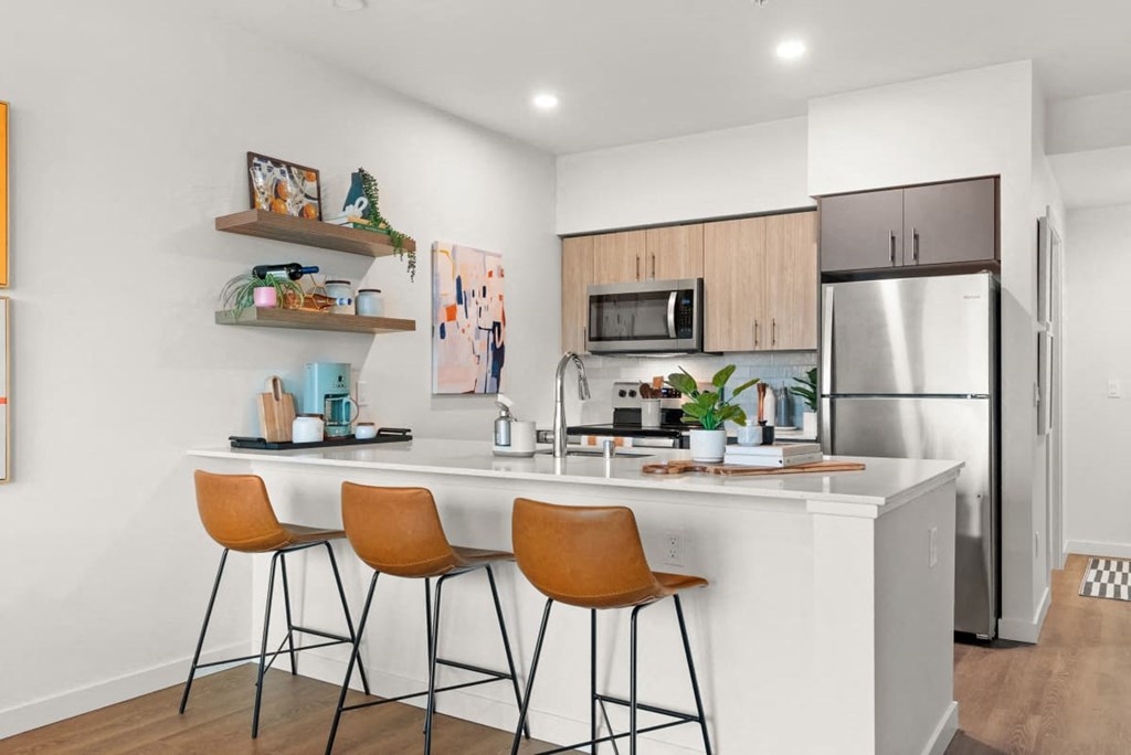 A kitchen with a white countertop and orange chairs. A kitchen with a white countertop and orange chairs at Cru at Willows Apartments, Redmond, WA