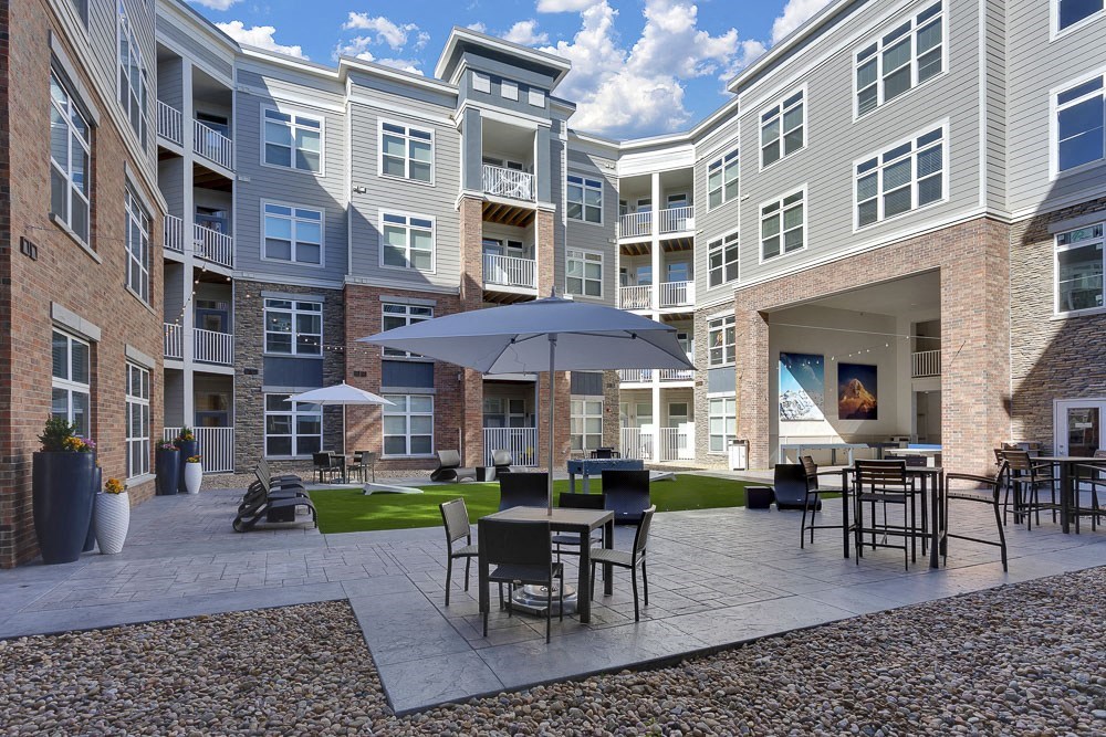 A patio with a table and chairs is surrounded by apartment buildings.