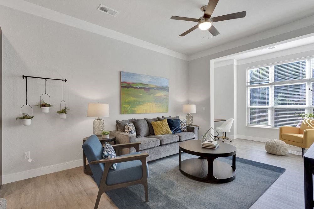 A living room with a grey sofa, a blue chair, a round coffee table, and a painting on the wall.