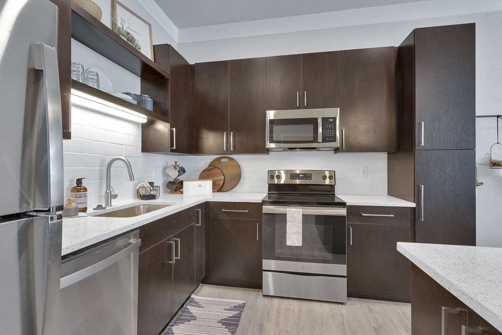 A modern kitchen with dark brown cabinets and stainless steel appliances.