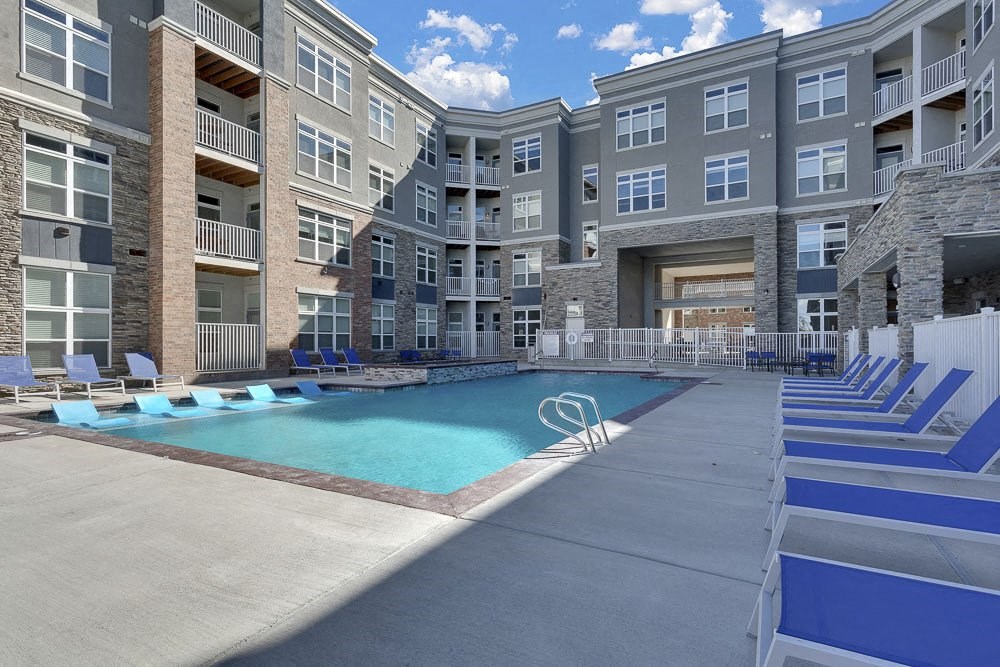 A large swimming pool is surrounded by apartment buildings.