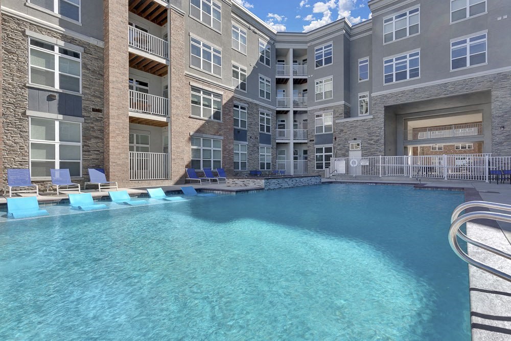 A large swimming pool in front of a multi-story residential building.