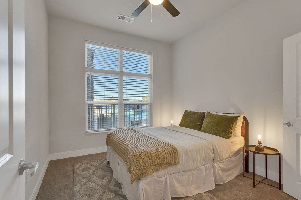 A bedroom with a bed, pillows, and a ceiling fan.
