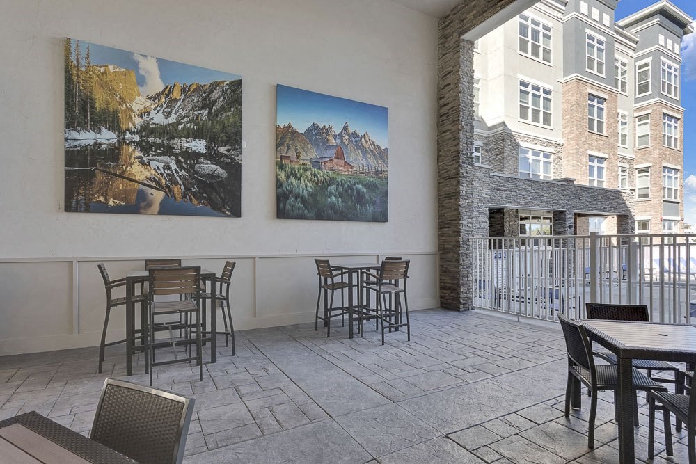 A patio with a table and chairs and two pictures on the wall.
