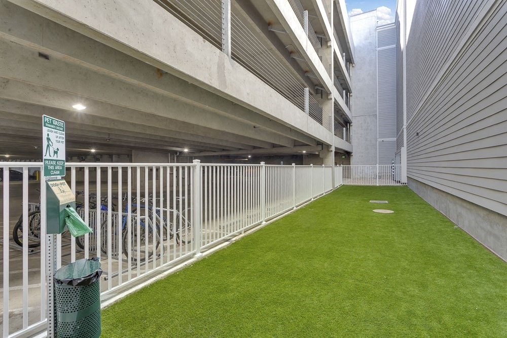 A parking garage with a green sign and a green trash can.