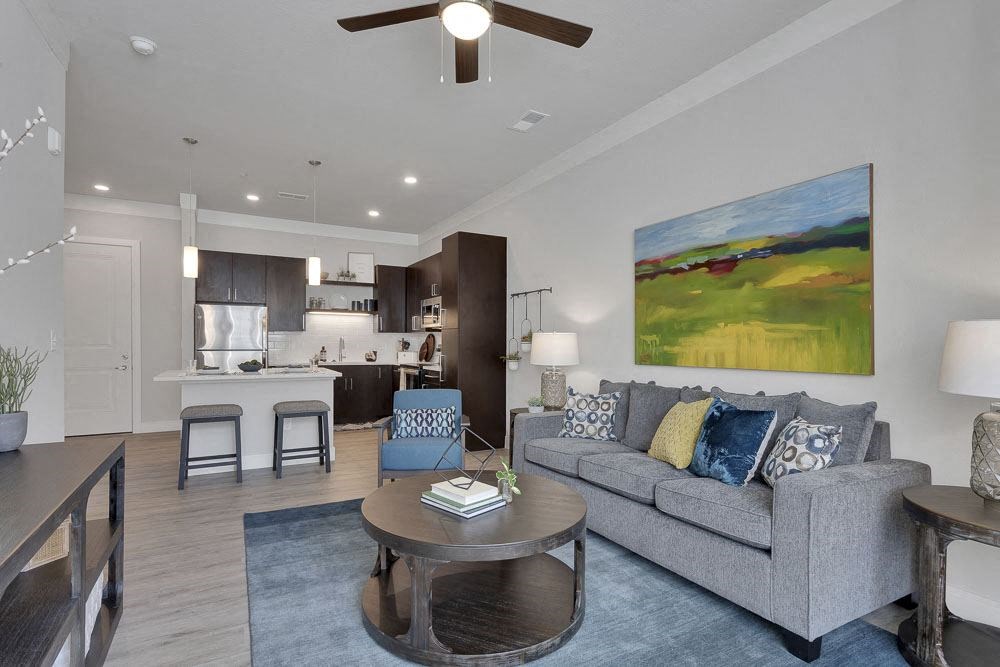 A living room with a grey couch and a painting on the wall.