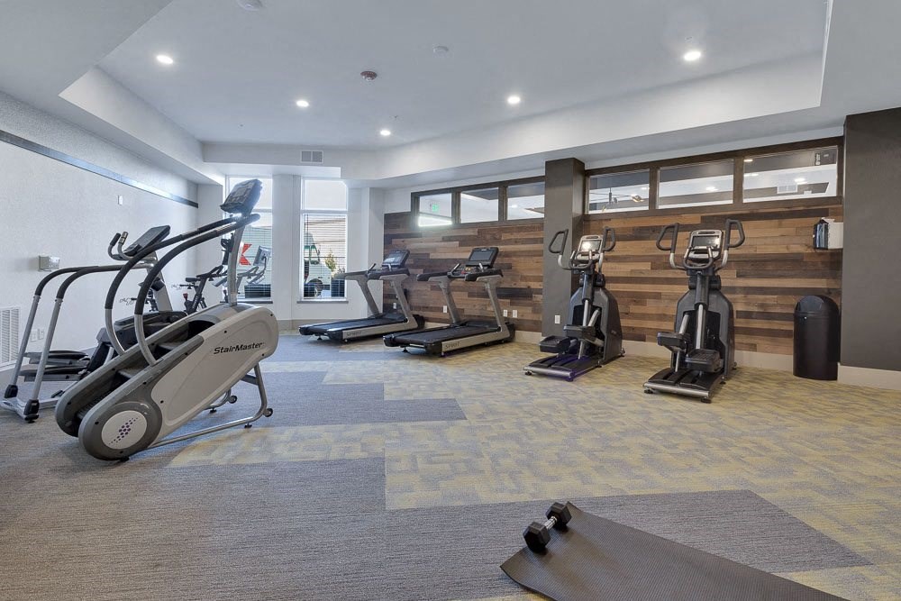 A gym with treadmills, elliptical machines, and a yoga mat.