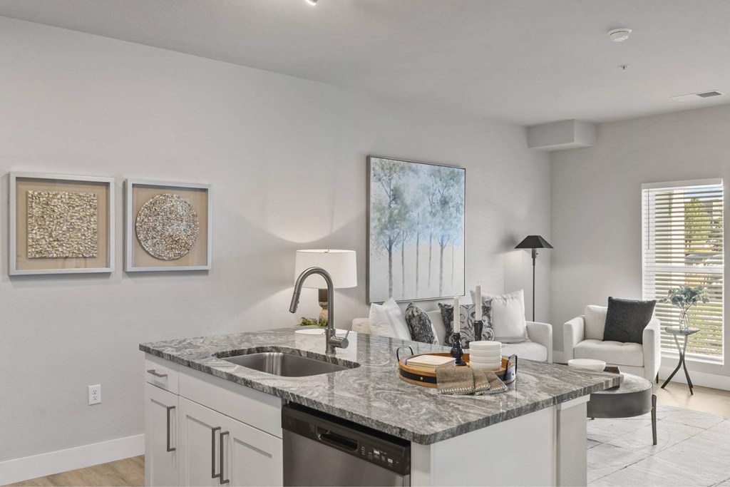 A modern kitchen with a marble countertop and white cabinets.