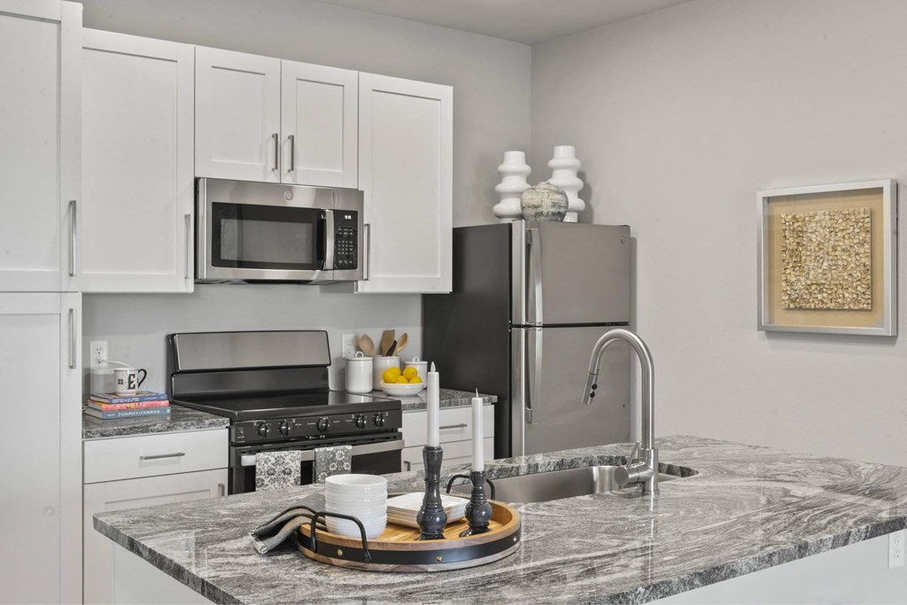 A kitchen with a marble countertop and stainless steel appliances.