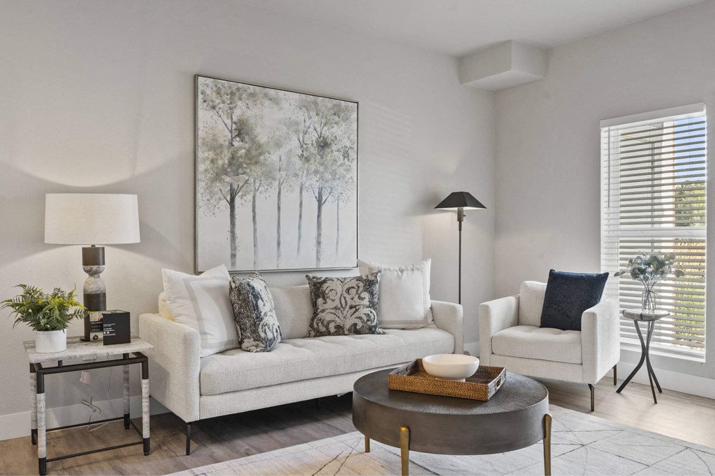 A living room with a white couch, a coffee table, and a painting on the wall.