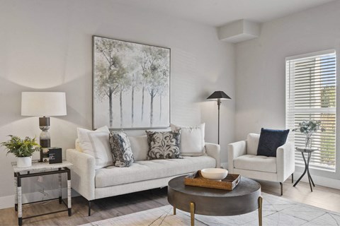 A living room with a white couch, a coffee table, and a painting on the wall.