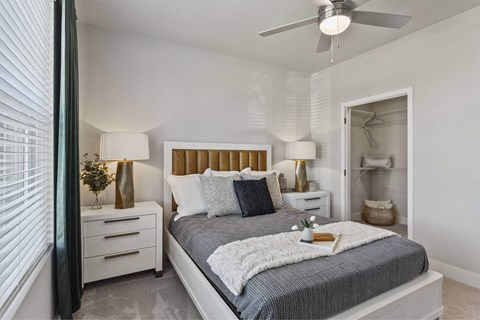 A bedroom with a bed, nightstands, and a ceiling fan.