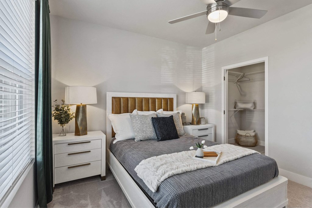 A bedroom with a bed, nightstands, and a ceiling fan.