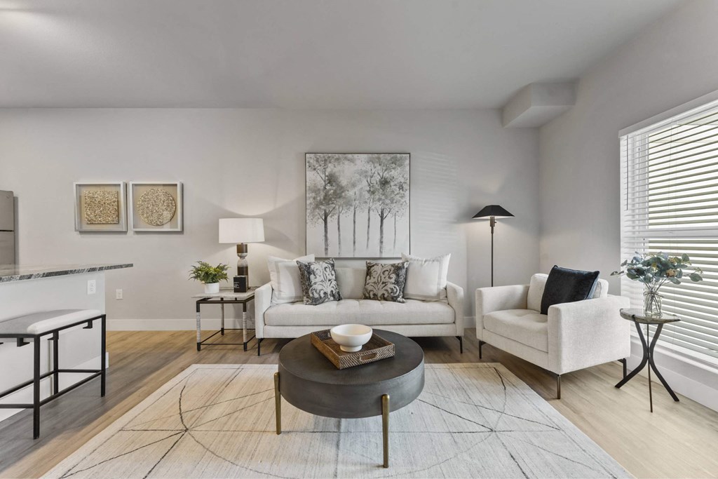 A living room with a white couch, a coffee table, and a painting on the wall.