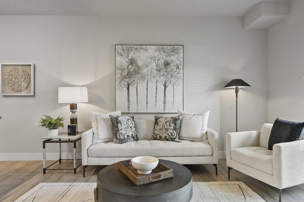 A living room with a white couch, a grey coffee table, and a painting on the wall.