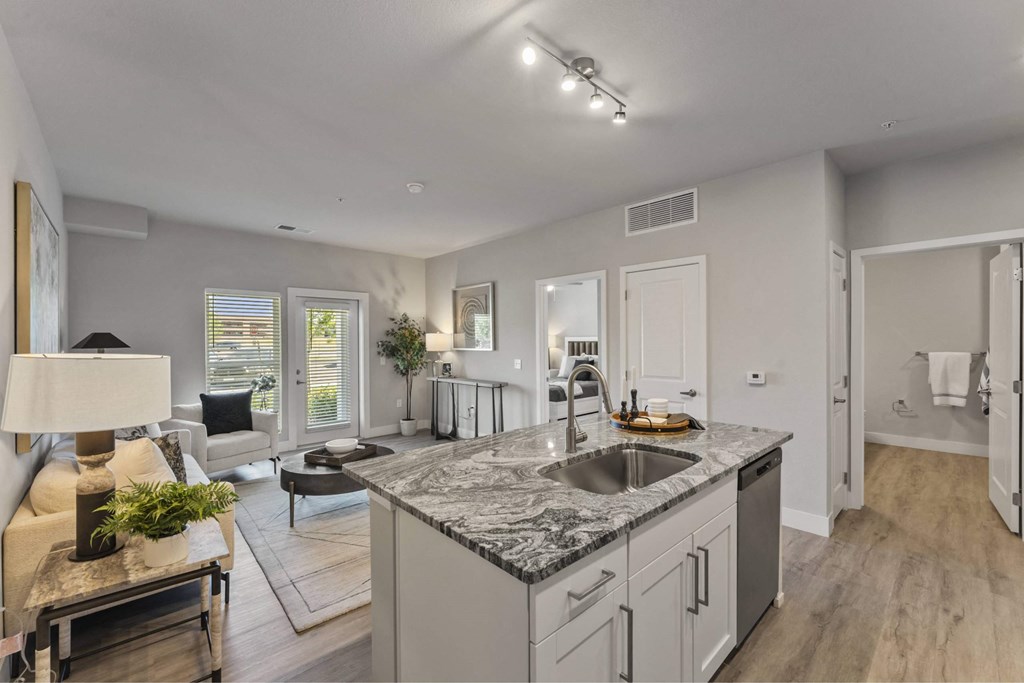 A modern kitchen with a marble countertop and stainless steel appliances.