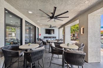 A patio with a table and chairs and a ceiling fan.