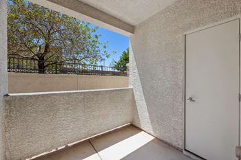 A balcony with a white door and a tree outside.