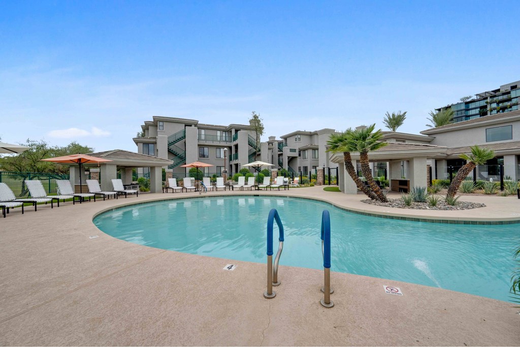 A swimming pool surrounded by lounge chairs and palm trees.