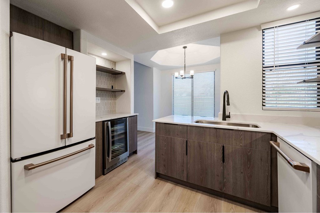 A modern kitchen with a white refrigerator and wooden cabinets.