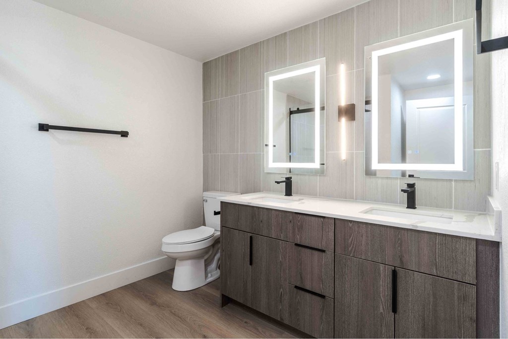 A bathroom with a toilet, sink, and mirrors.